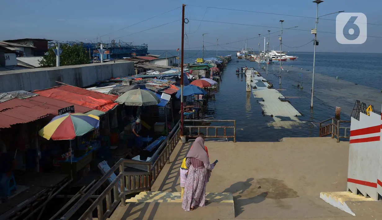 Akivitas warga saat terjadinya banjir rob di Pelabuhan Kali Adem, Muara Angke Jakarta, Rabu (5/1/2022). Menurut BMKG, adanya fase bulan baru yang bersamaan dengan masa Perigee (jarak terdekat bulan bumi) menyebabkan peningkatan signifikan ketinggian pasang air laut. (merdeka.com/Imam Buhori)