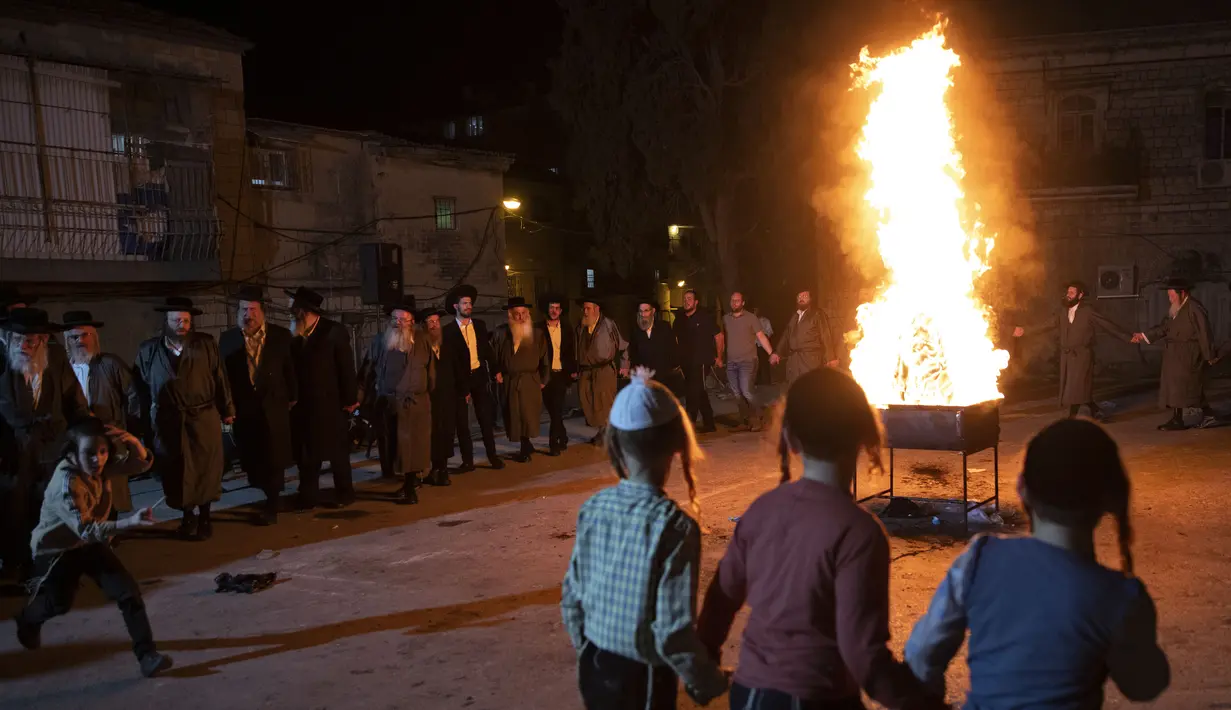 Yahudi Ultra-Ortodoks menari  di samping api unggun selama hari libur Yahudi perayaan Lag Ba'Omer di Bnei Brak, Israel, Kamis (29/4/2021). Liburan Lag Ba'Omer, menandai berakhirnya wabah yang dikatakan telah membinasakan orang Yahudi selama zaman Romawi. (AP Photo/Sebastian Scheiner)