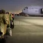 Orang-orang Afghanistan mengantre dan menaiki pesawat militer AS untuk meninggalkan Afghanistan, di bandara militer di Kabul, Kamis (19/8/2021). Ribuan orang berlomba-lomba melarikan diri dari Afghanistan setelah pasukan Taliban berhasil merebut pemerintahan negara itu. (Shakib RAHMANI/AFP)