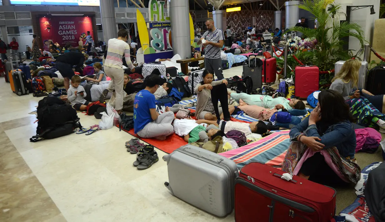 Turis asing bersantai dengan alas seadanya di lantai Bandara Internasional Lombok Praya, NTB, Senin (6/8). Imbas gempa 7 skala Richter, para wisatawan mancanegara terlantar di bandara karena jam pemberangkatan pesawat yang tertunda. (AFP/SONNY TUMBELAKA)