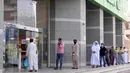 Orang-orang mengenakan masker mengantre di luar sebuah toko ketika langkah-langkah penguncian dilonggarkan di tengah pandemi Covid-19 di kota suci Mekah Arab Saudi (31/5/2020). (AFP Photo/Bandar al-Dandani)