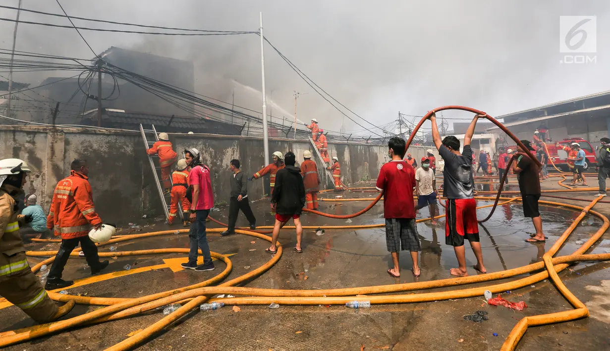 Petugas pemadam kebakaran bersana warga mencoba memadamkan api yang membakar pemukiman padat penduduk di kawasan Manggarai, Jakarta, Rabu (10/7/2019). Belum diketahui pasti penyebab api membakar pemukiman warga tersebut. (Kapanlagi.com/Budy Santoso)