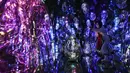 Seorang wanita bertopeng memberi isyarat saat pengunjung berinteraksi dengan instalasi seni digital imersif berjudul “Resonating Microcosms, Solidified Light Color” di museum "teamLab Massless" yang baru dibuka di Beijing, China, Senin (26/12/2022). Berbasis di Tokyo teamLab membuat museum seni digital yang memamerkan berbagai karya seni interaktif di dalam pusat perbelanjaan di ibu kota Beijing. (AP Photo/Andy Wong)