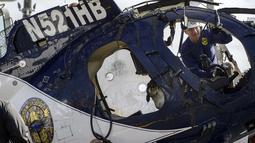 Penyelidik dari Badan Keselamatan Transportasi Nasional, NTSB, memotret puing-puing helikopter di Pantai Newport, California (20/2/2022). Kecelakaan menewaskan Petugas Pantai Huntington Nicholas Vella, seorang veteran pasukan selama 14 tahun. (Mindy Schauer/The Orange County Register via AP)