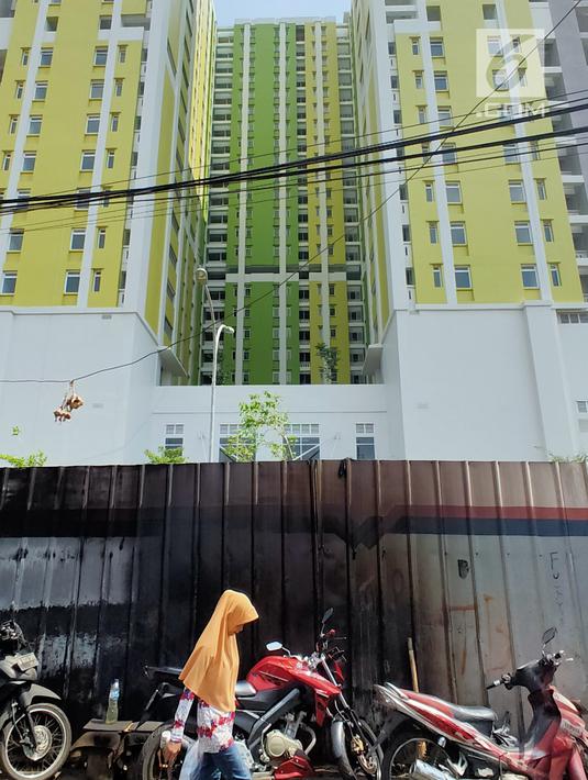 Warga berjalan dekat proyek Rusunawa Pasar Rumput yang hampir selesai pengerjaannya di Jakarta, Selasa (16/7/2019). Proyek yang dimulai sejak 2016 lalu tersebut memiliki 1.984 unit hunian serta 1.314 kios. (Liputan6.com/Immanuel Antonius)