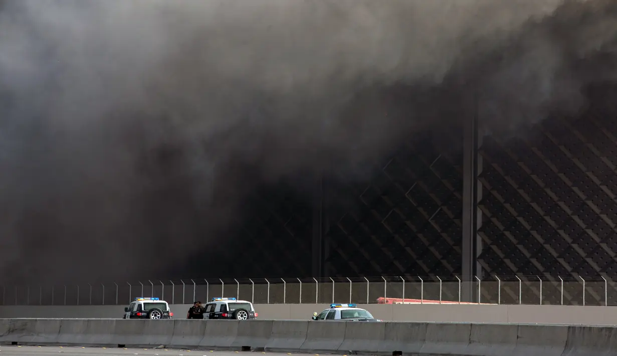 Petugas kepolisian terlihat saat asap hitam  membumbung menyelimuti gedung Stasiun Kereta Api Cepat Haramain di kota Jeddah, Minggu (29/9/2019). Insiden memaksa keamanan segera menutup jalan utama yang menghubungkan Jeddah dengan Makkah. (Photo by - / AFP)