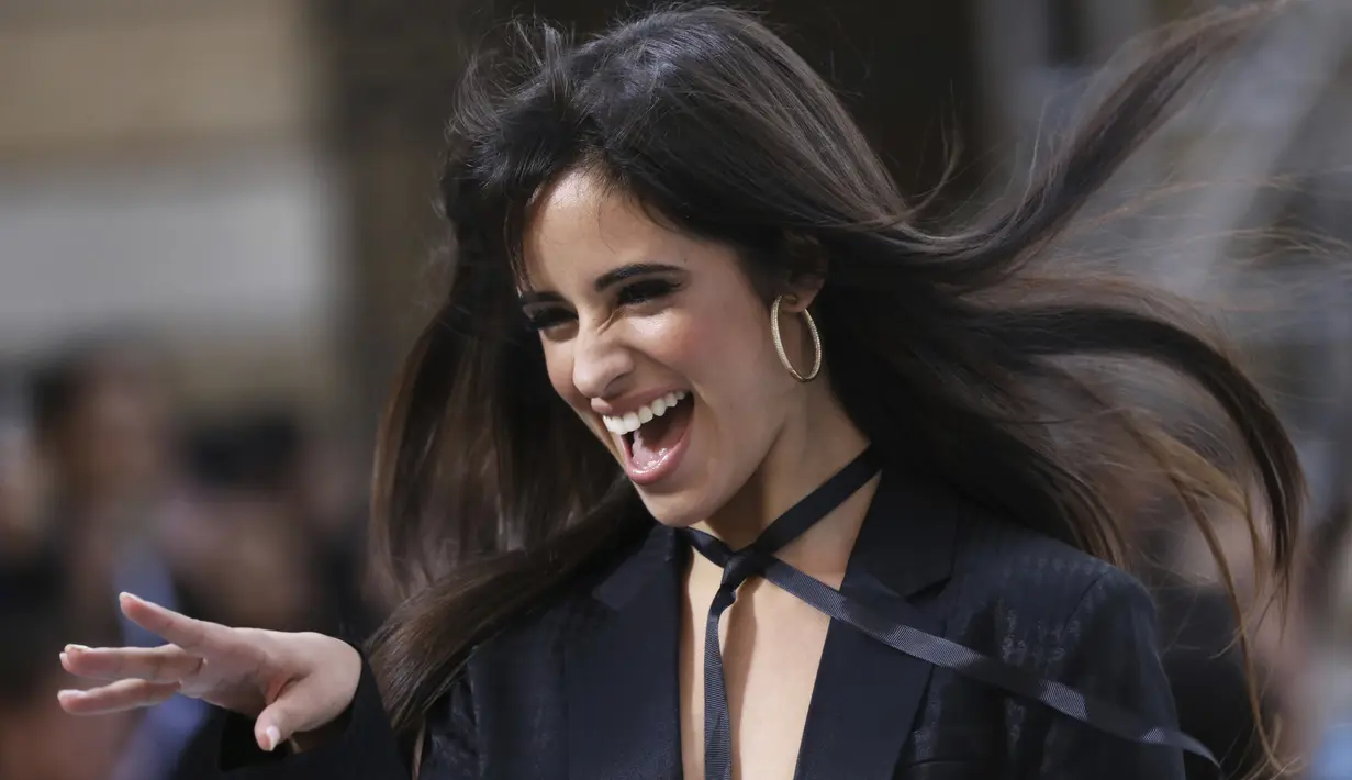 Camila Cabello tertawa saat berjalan di catwalk memakai kreasi dari koleksi L'Oreal Ready To Wear Spring-Summer 2020 selama pekan mode di Paris (28/9/2019). Penyanyi 22 tahun ini tampil seksi mengenakan blazer dan celana hitam yang menjuntai di landasan. (Photo by Vianney Le Caer/Invision/AP)