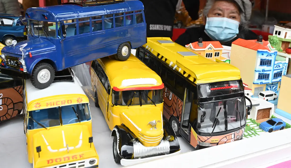 Seorang perempuan menjual bus mini di kios pinggir jalan selama Alasitas Fair tahunan di La Paz, Bolivia pada 24 Januari 2022. Orang-orang membeli replika kecil dari barang-barang yang ingin mereka peroleh sepanjang tahun, seperti rumah, mobil, dan kekayaan. (AIZAR RALDES/AFP)