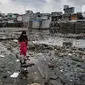 Seorang anak melintasi genangan sampah di permukiman kumuh Muara Baru, Jakarta, Rabu (19/1/2022). Badan Pusat Statistik (BPS) mencatat angka kemiskinan Indonesia turun menjadi 26,5 juta orang per September 2021 dari sebelumnya mencapai 27,54 juta orang pada Maret 2021. (merdeka.com/Iqbal S Nugroho)