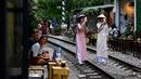 Foto pada 8 Juni 2019 menunjukkan uris mengenakan kostum tradisional Vietnam berswafoto di tengah jalur kereta api populer di Hanoi. Di ibu kota Vietnam tersebut rel-rel kereta yang berada di permukiman padat penduduk dijadikan destinasi wisata selfie. (Photo by Manan VATSYAYANA / AFP)