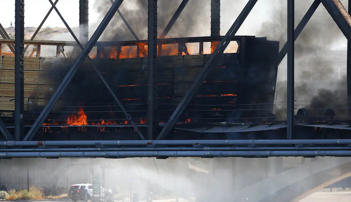 Kereta barang tergelincir dan terbakar di jembatan Danau Kota Tempe, Arizona, Amerika Serikat, Rabu (29/7/2020). Beberapa mobil yang dimuat kereta tersebut dilaporkan turut terbakar. (AP Photo/Ross D. Franklin)