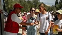 Suhu Yunani memanas. Seorang anggota organisasi Palang Merah Hellenic membagikan air dingin kepada wisatawan di dekat pintu masuk situs arkeologi Acropolis di Athena pada 20 Juli 2023. (AFP)