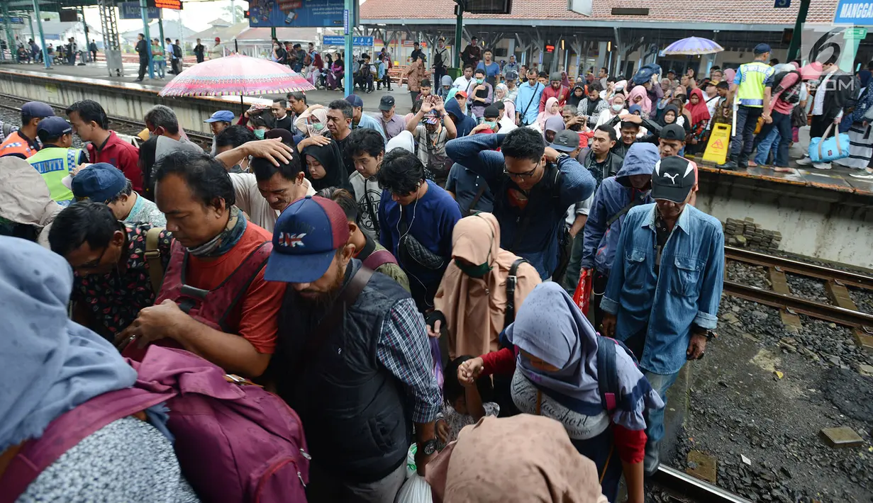 Penumpang kereta commuter line menyeberang rel kereta di Stasiun Manggarai, Jakarta, Selasa (22/1). PT. Kereta Commuter Indonesia (KCI) menutup jalur 10 di Stasiun Manggarai guna mempercepat revitalisasi yang sedang dilakukan. (Merdeka.com/Imam Buhori)