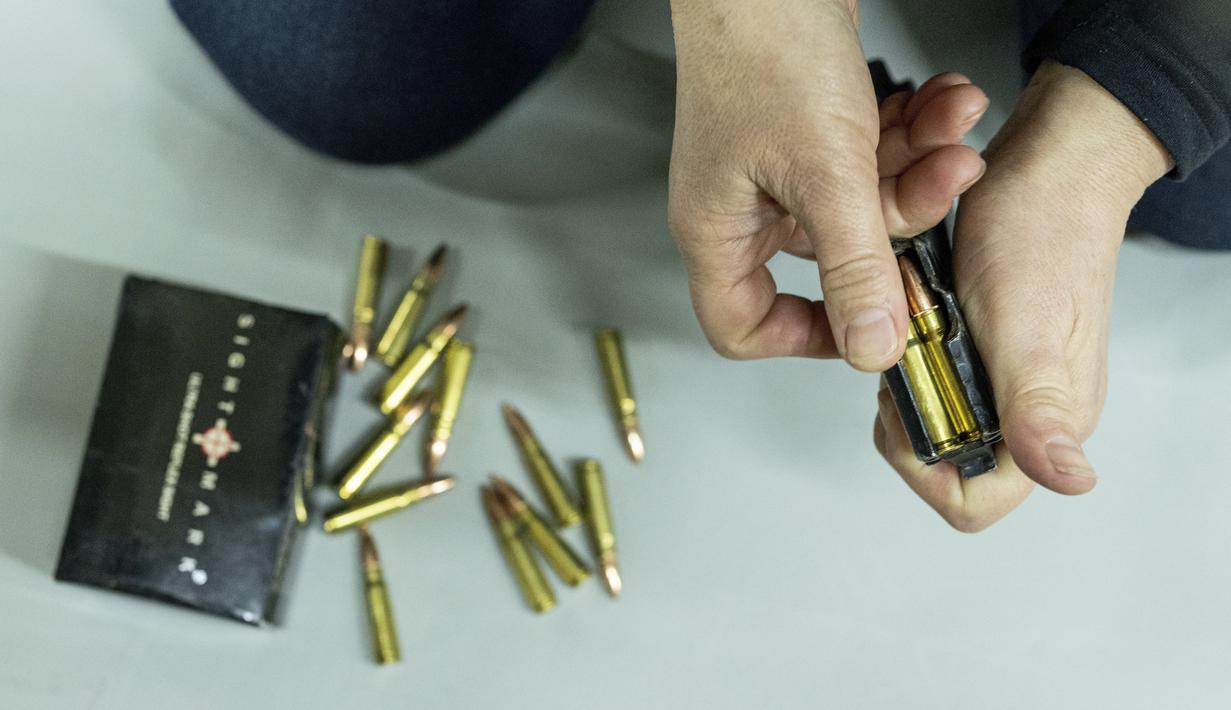 Seorang wanita mengisi amunisi untuk senapan serbu Kalashnikov selama pelatihan di Kharkiv, Ukraina (30/1/2022). Beberapa orang di kota terbesar kedua di Ukraina bersiap untuk melawan jika Rusia menyerang. (AP Photo/Evgeniy Maloletka)