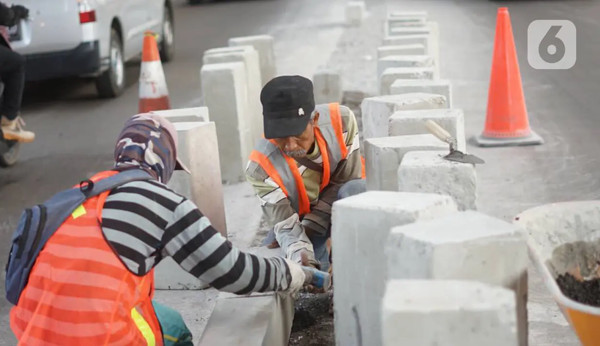 Pekerja menyelesaikan pembuatan separator atau pembatas jalan di Jalan Margasatwa, Andara, Jakarta Selatan, Kamis (21/11/2019). Separator itu dibuat guna memisahkan dua lajur sehingga meminimalisasi tingkat kecelakaan. (Liputan6.com/Immanuel Antonius)