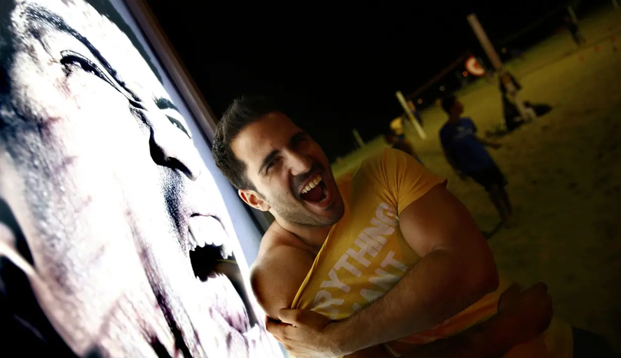 Salah satu pengunjung pantai Copacabana, Rio de Janeiro, Brasil, (26/6/2014), berekspresi di depan iklan bergambar Luis Suarez. (REUTERS/Kai Pfaffenbach)