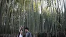 Wisatawan mengenakan kimono sambil berswafoto saat mengunjungi Hutan Bambu Sagano di Arashiyama, Kyoto pada 8 Desember 2018. Karena keindahan hutan bambunya, membuat kawasan wisata ini menjadi sangat terkenal di Jepang. (Behrouz MEHRI / AFP)