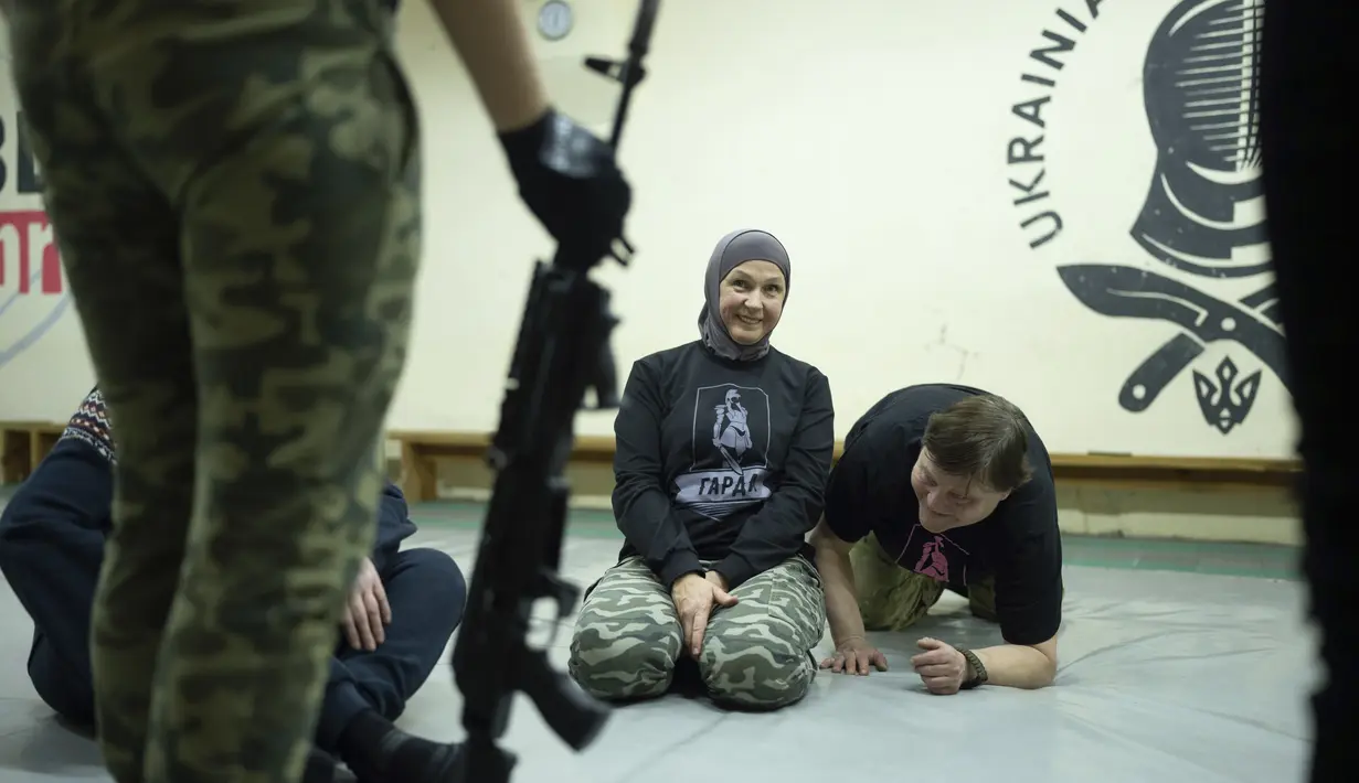Svetlana Putilina tersenyum saat mendengarkan instruktur selama pelatihan di Kharkiv, Ukraina (30/1/2022). Dengan tekad yang kuat dan tidak sedikit pun panik, wanita berusia 50 tahun itu telah mengatur rencana darurat untuk keluarganya dan unitnya. (AP Photo/Evgeniy Maloletka)