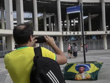Seorang pria mengambil foto plang dengan nama baru jalan yang mengelilingi stadion Maracana, yang sekarang akan dikenal sebagai King Pele Avenue di Rio de Janeiro, Brasil, 4 Desember 2022. Perubahan nama tersebut sebagai penghargaan untuk legenda sepak bola Brasil, Edson Arantes do Nascimento atau lebih dikenal sebagai Pele. (AP Photo/Bruna Prado)