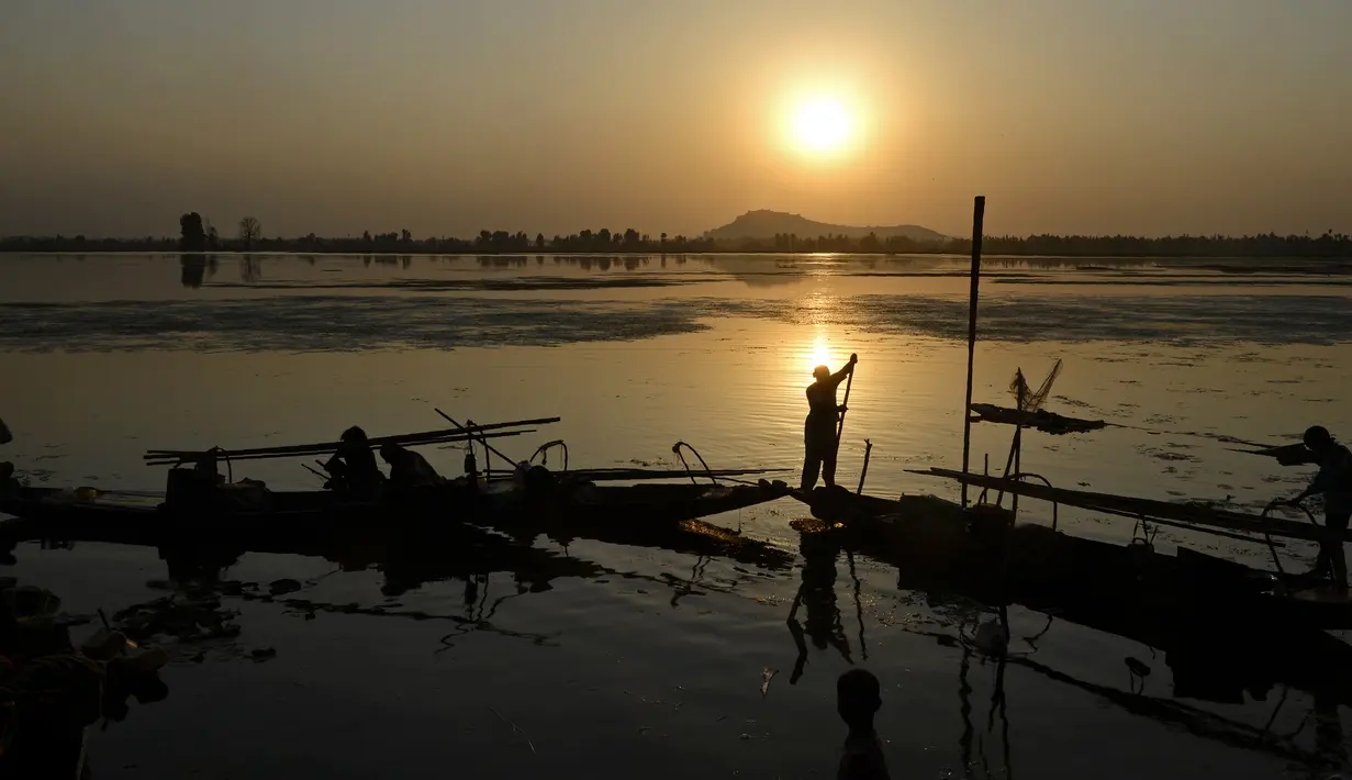 Aktivitas nelayan Kashmir saat matahari terbenam di danau Dal di Srinagar, India (12/9). Danau Dal yang luas dan bening. Diatasnya terhampar gerombolan daun bunga lotus. (AFP Photo/Tauseef Mustafa)