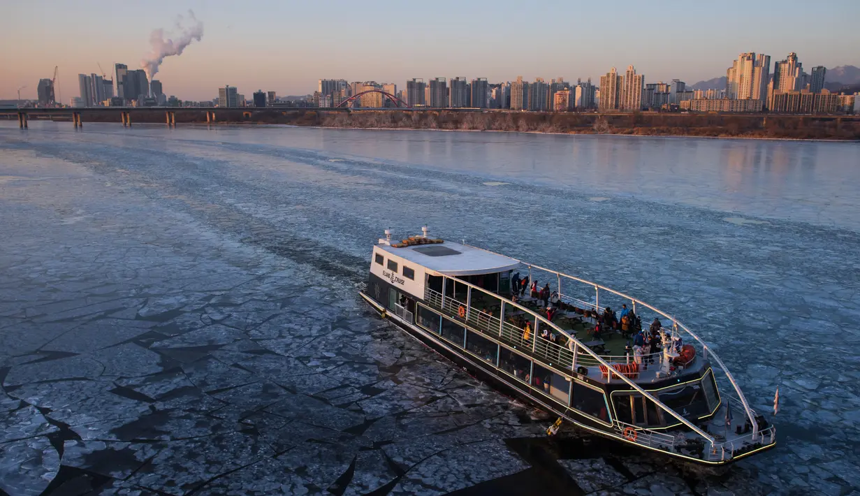 Sebuah kapal penumpang berlayar melewati aliran es di Sungai Han yang membeku di Seoul, Korea Selatan, Senin (25/1). Suhu terendah dalam 15 tahun terakhir terjadi di Seoul yaitu 18 derajat Celcius. (AFP PHOTO / Ed Jones)