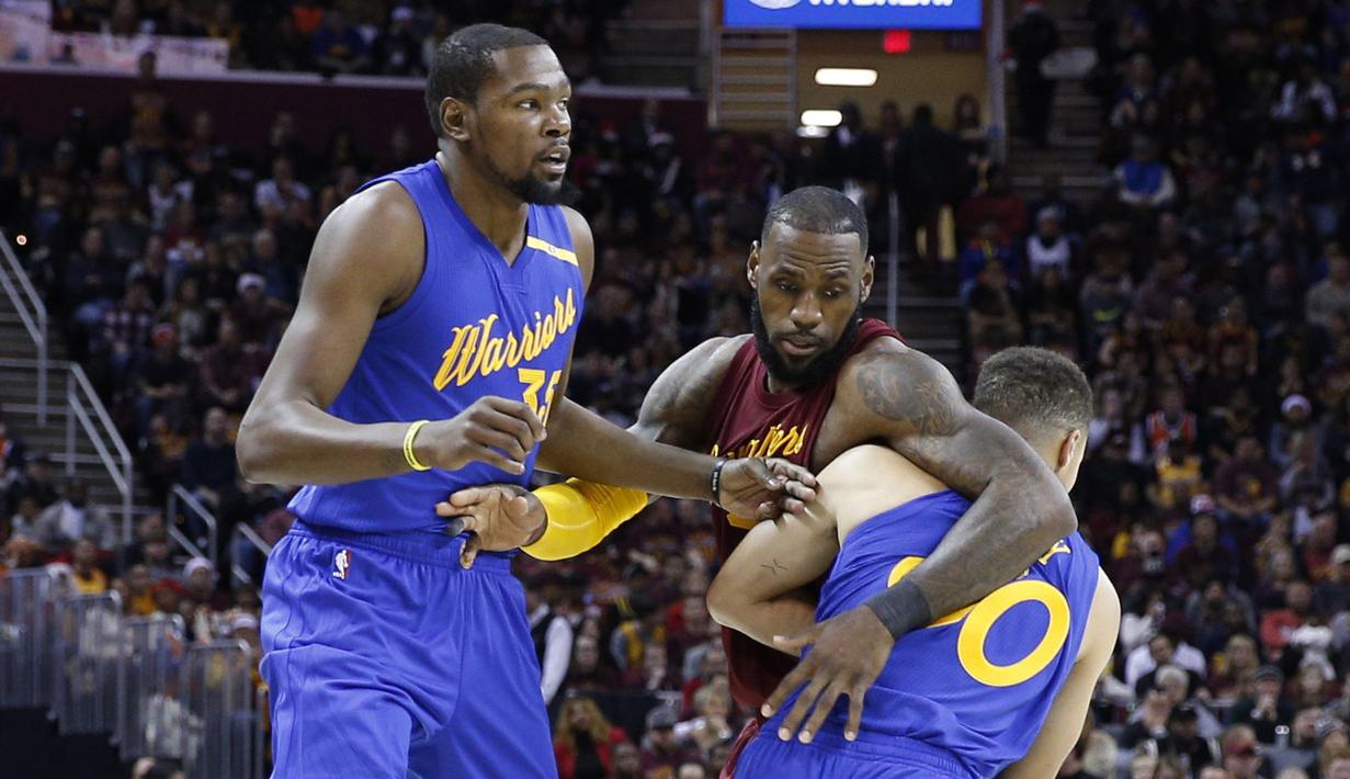 Pemain Warriors,  Kevin Durant (kiri) dan Stephen Curry (kanan) menghadang pergerakan pemain   Cleveland Cavaliers, LeBron James pada laga NBA di Quicken Loans Arena, (25/12/2016). Cleveland menang 109-108. (Reuters/Brian Spurlock-USA TODAY Sports)