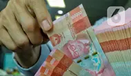 Pegawai menata mata uang rupiah di salah satu gerai penukaran mata uang di Jakarta, Kamis (5/1/2023). Nilai tukar rupiah ditutup di level Rp15.616 per dolar AS pada Kamis (5/1) sore ini. Mata uang Garuda melemah 34 poin atau minus 0,22 persen dari perdagangan sebelumnya. (Liputan6.com/Angga Yuniar)