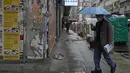 Seorang pria yang mengenakan masker, melintasi jalan di Hong Kong, pada 22 Februari 2022. Hong Kong akan melakukan pengujian Covid-19 untuk seluruh penduduknya pada bulan Maret mendatang, saat kota itu bergulat dengan wabah terburuk dari varian omicron. (AP Photo/Kin Cheung)
