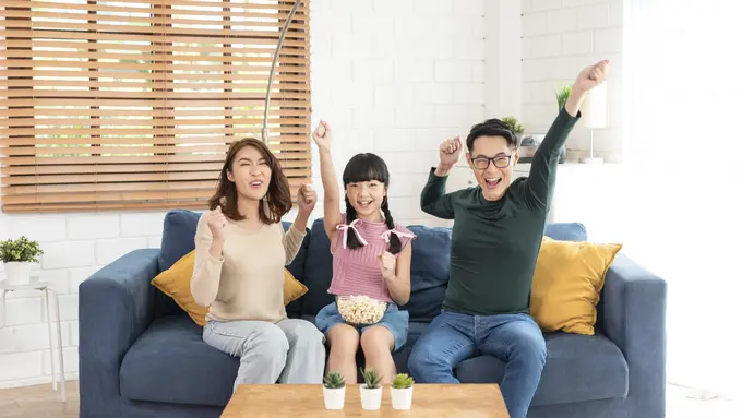 Sebuah keluarga kecil sedang bersorak gembira di ruang keluarga (Foto Dok: Freepik/our-team)