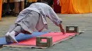 Seorang biksu menunjukkan kemampuann push up dengan dua jari selama kompetisi seni bela diri '72 Arts of Shaolin' di kuil Shaolin di Provinsi Henan, China, 30 Juli 2017. Kompetisi ini menampilkan para jago kungfu yang memamerkan kekuatan fisik. (STR AFP)