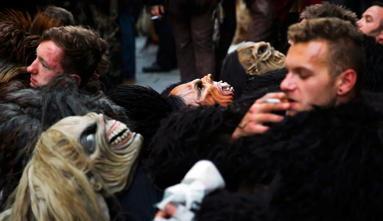 Sejumlah orang tampak beristirahat selama mengikuti parade di Munich, Jerman, Minggu (13/12). Krampuss diceritakan sebagai teman Saint Nicholas untuk datang ke rumah - rumah.  (REUTERS/Michael Dalder)