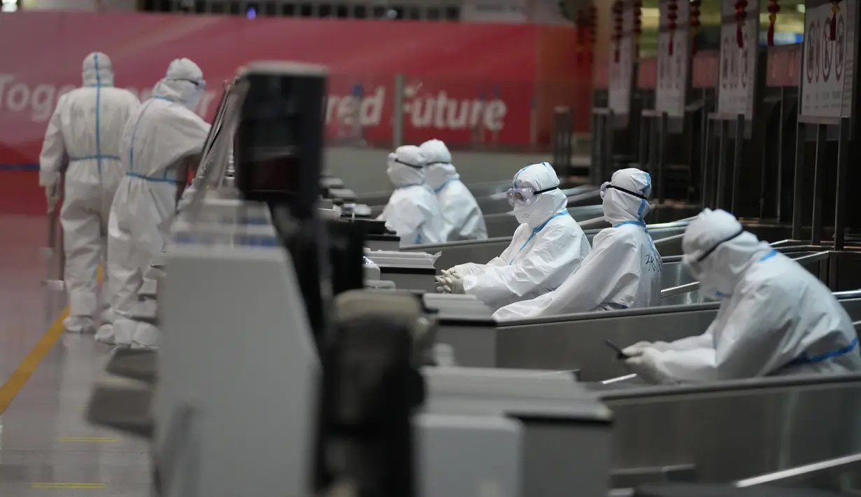Pekerja Olimpiade dengan pakaian pelindung membantu para pelancong di bandara Internasional Ibu Kota Beijing setelah Olimpiade Musim Dingin 2022, di Beijing, China, Senin (21/2/2022). (APhoto/Frank Augstein)