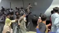 Ratusan orang berusaha menaiki pesawat angkut C-17 Angkatan Udara AS di landasan bandara internasional, di Kabul, Afghanistan (16/8/2021).  Di tengah kekacauan pasca direbutnya Ibukota Kabul oleh pasukan Taliban, dua warga jatuh dari pesawat militer Amerika Serikat. (Verified UGC via AP)