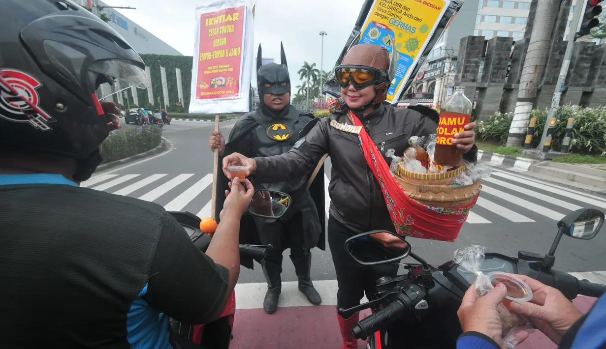 Warga mengenakan kostum superhero Gundala dan Batman menawarkan minuman herbal tradisional Indonesia “Jamu” kepada pengendara saat aksi sosialisasi pencegahan virus corona di Solo (4/3/2020). Jamu dapat meningkatkan daya tahan tubuh agar terhindar dari berbagai penyakit. (AFP Photo/Anwar Mustafa)