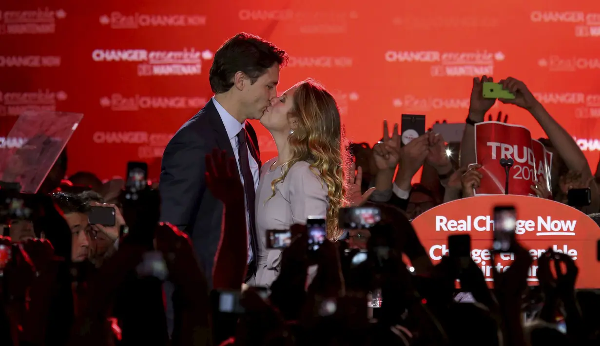 Pemimpin Partai Liberal, Justin Trudeau mencium istrinya Sophie Gregoire usai pemilihan umum di Montreal, Quebec, Kanada, Senin (19/10). Trudeau mengakhiri kekuasaan sembilan tahun PM Stephen Harper dari Partai Konservatif. (Reuters/ Chris Wattie)