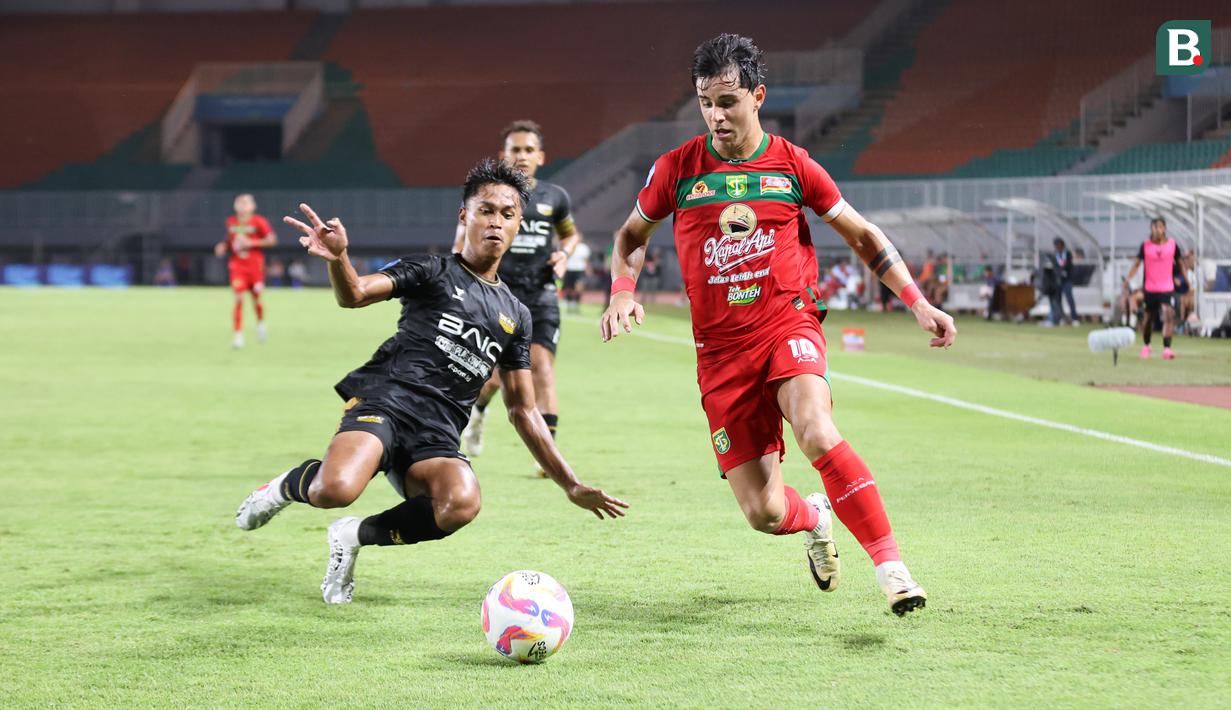 Pemain Persebaya Surabaya, Bruno Moreira, mencoba melewati hadangan dari pemain Dewa United, Alfriyanto Nico, dalam pertandingan Dewa United melawan Persebaya Surabaya pada pekan ke-24 BRI Liga 1 di Stadion Pakansari, Kabupaten Bogor, Jumat (21/2/2025) malam WIB. (Bola.com/Abdul Aziz)