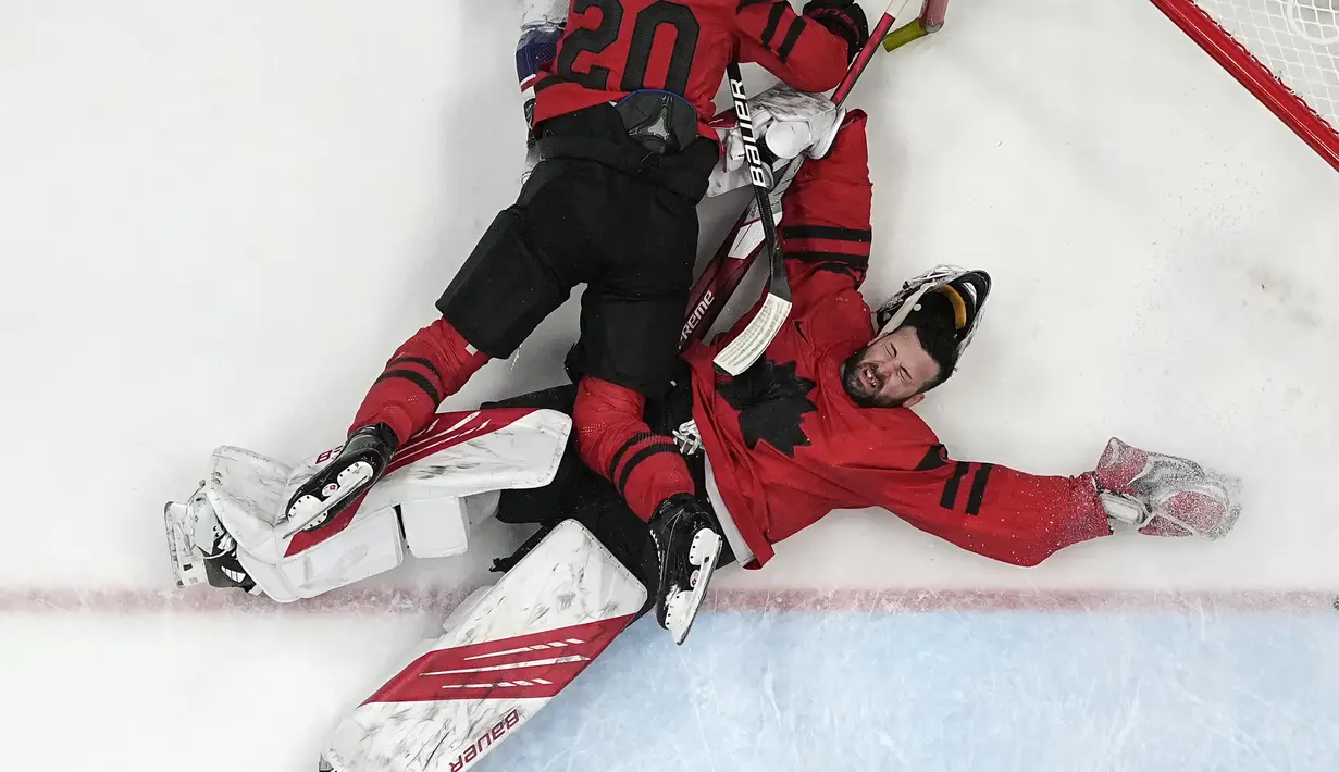 Kiper Kanada Eddie Pasquale dijatuhkan oleh rekan setimnya Alex Grant (20) selama pertandingan hoki putra babak penyisihan melawan Amerika Serikat di Olimpiade Musim Dingin 2022, Sabtu, 12 Februari 2022, di Beijing. (AP Photo/Matt Slocum)