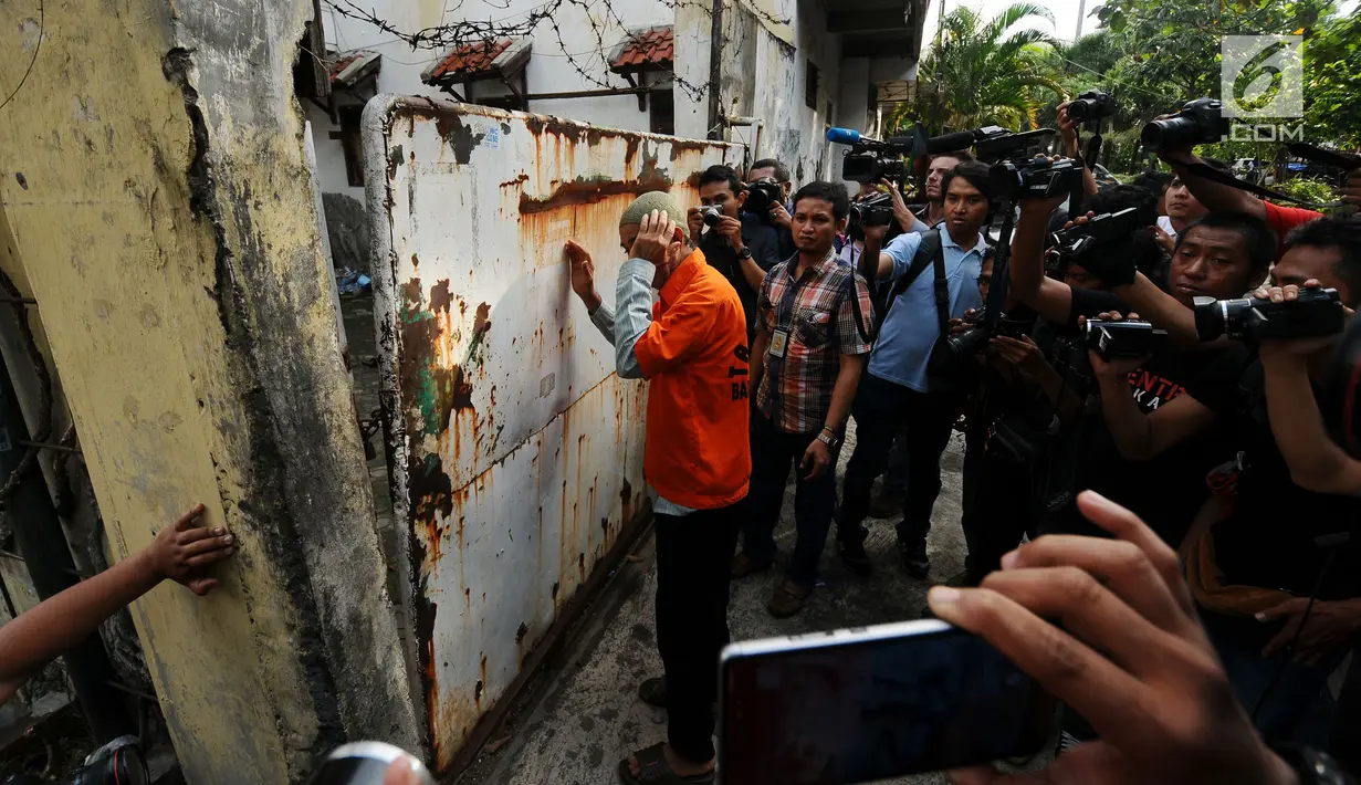 Tersangka penampung TKI Ilegal bersiap masuk ke dalam rumah di Jalan Percetakan Negara X, Jakarta, Rabu (31/5). Bersama satu tersangka, petugas Dirtipidum Mabes Polri melakukan pencarian barang bukti baru. (Liputan6.com/Helmi Fithriansyah)