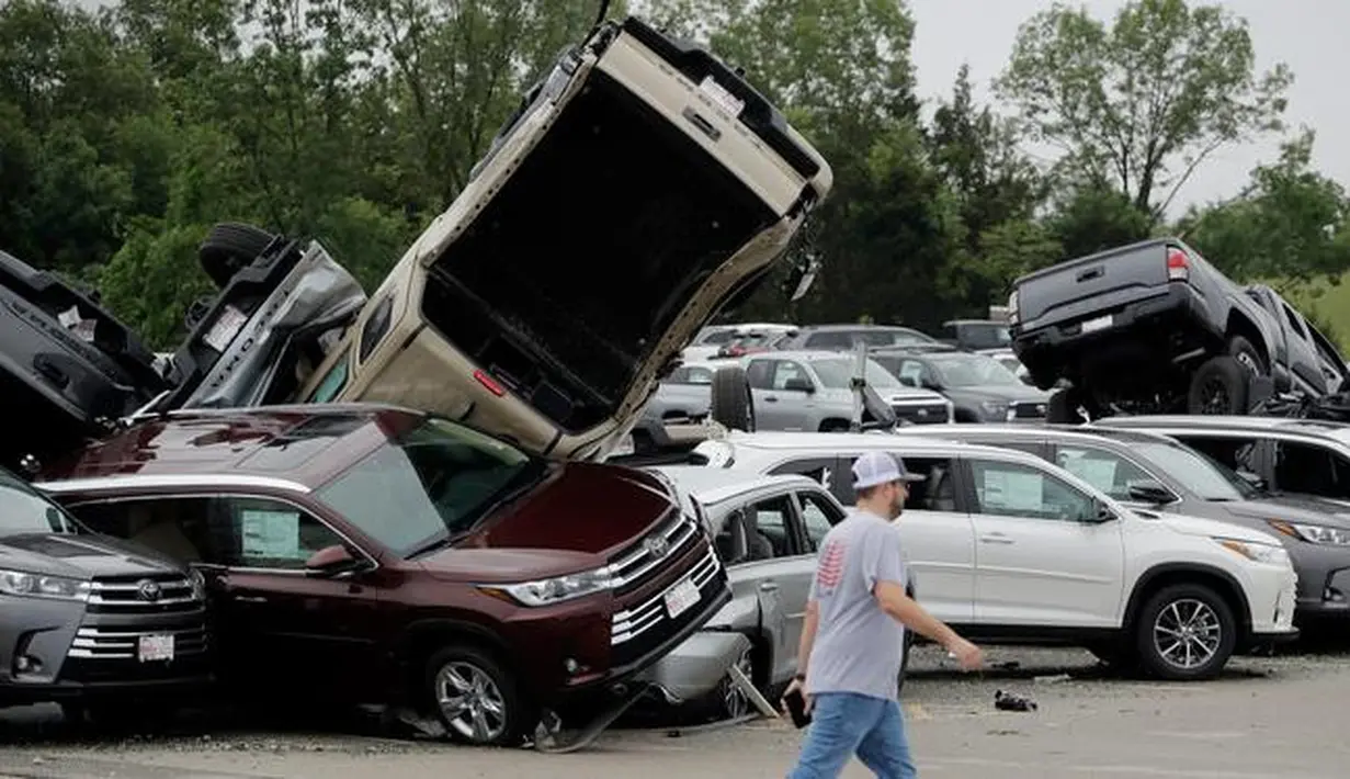 Seorang pekerja berjalan melewati deretan mobil yang rusak akibat tornado di sebuah dealer di Jefferson City, Missouri, AS, Kamis (23/5/2019). Tiga orang tewas akibat tornado yang menyapu Missouri sehari sebelumnya. (AP Photo/Charlie Riedel)