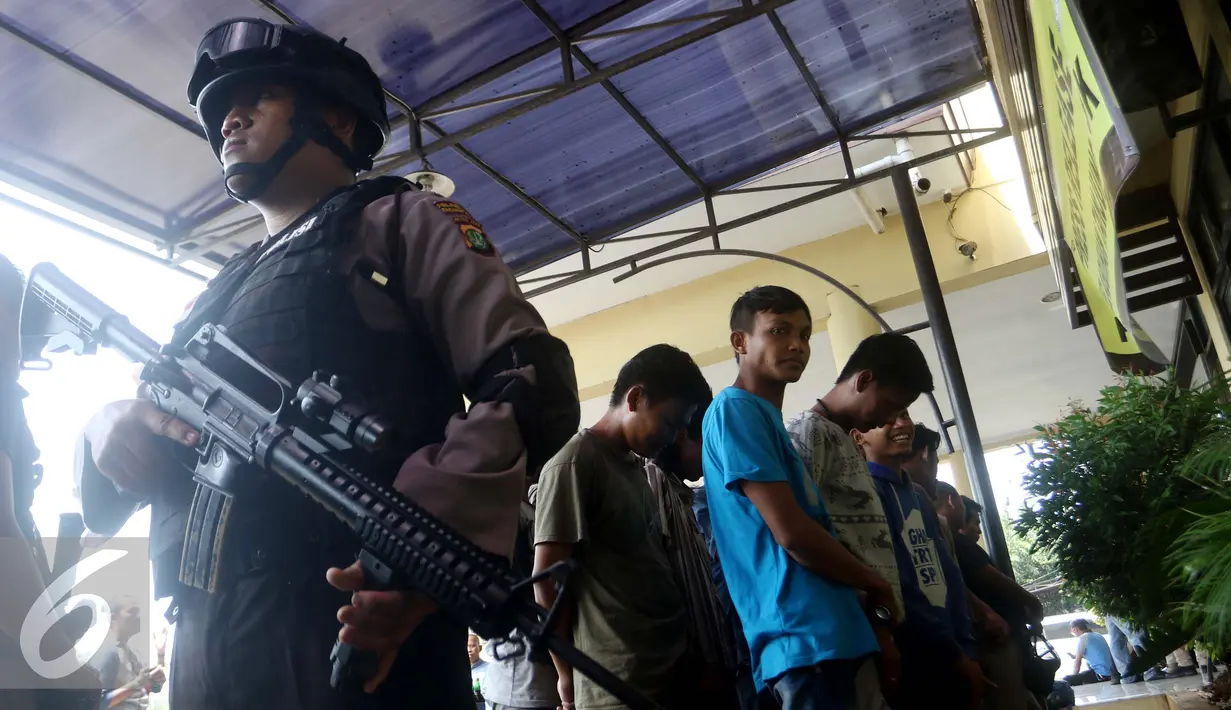 Polisi dengan senjata lengkap menjaga para tersangka saat rilis di halaman Polres Metro Pelabuhan Tanjung Priok, Kamis (27/10). (Liputan6.com/Gempur M. Surya)
