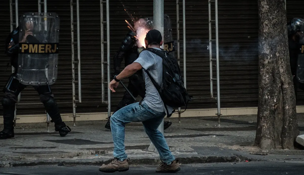 Pengunjuk rasa melemparkan petasan ke arah polisi saat bentrokan memprotes rencana pembatasan belanja publik di Rio de Janeiro, Brasil, (9/2). (AFP Photo / Yasuyoshi Chiba)