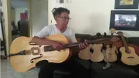 Erwan Prasetyo atau Wawan memainkan cello yang terbuat dari kayu peti kemas buatannya, Sabtu (15/9 - 2018). (Madiunpos.com/AbdulJalil)