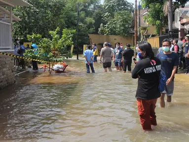 Warga memantau banjir akibat jebolnya tanggul karena tertimpa tanah longsor, di Perumahan Nerada Estate Ciputat, Tangerang Selatan, Sabtu (12/6/2021). Longsor yang menimpa sejumlah rumah membuat tanggul pembatas kali jebol dan air meluap sehingga menyebabkan banjir. (Liputan6.com/Angga Yuniar)