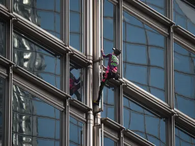Alain Robert yang dijuluki 'French Spiderman' memanjat gedung pencakar langit Cheung Kong Center di Hong Kong, Jumat (16/8/2019). Pria berusia 57 tahun tersebut memanjat Cheung Kong Center dalam kondisi panas dan lembab pada Jumat pagi. (Lillian SUWANRUMPHA/AFP)