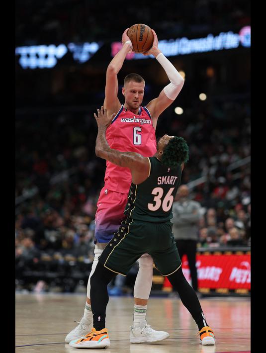 Pemain Washington Wizards, Kristaps Porzingis (kiri) berebut bola dengan pemain Boston Celtics, Boston Celtics pada laga NBA 2023 di Capital One Arena, Washington, 28 Maret 2023. (AFP/Getty Images/Patrick Smith)