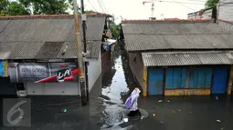 Warga melawati jalanan yang banjir di kawasan Jakarta Barat, Jumat (26/2). Banjir terjadi juga dikarenakan kali Daan Mogot yang  tak kunjung surut. (Liputan6.com/Faisal R Syam)