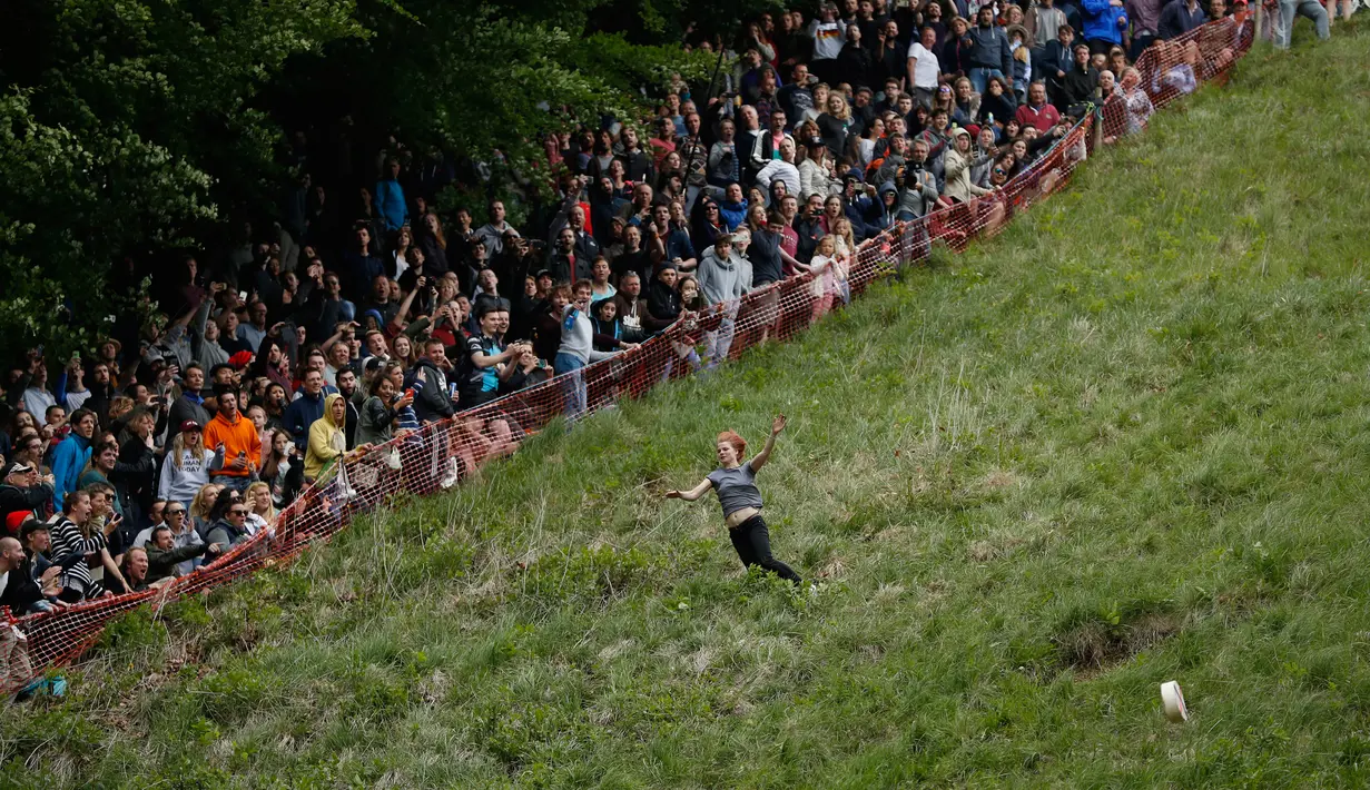 Florence Early berlomba mengambil bagian dalam tradisi tahunan kompetisi keju bergulir atau Cheese Rolling di Coopers Hill, Gloucestershire Inggris, 30 Mei 2016. Tradisi tersebut telah dilakukan sejak sekitar tahun 1800-an. (Adrian DENNIS/AFP)