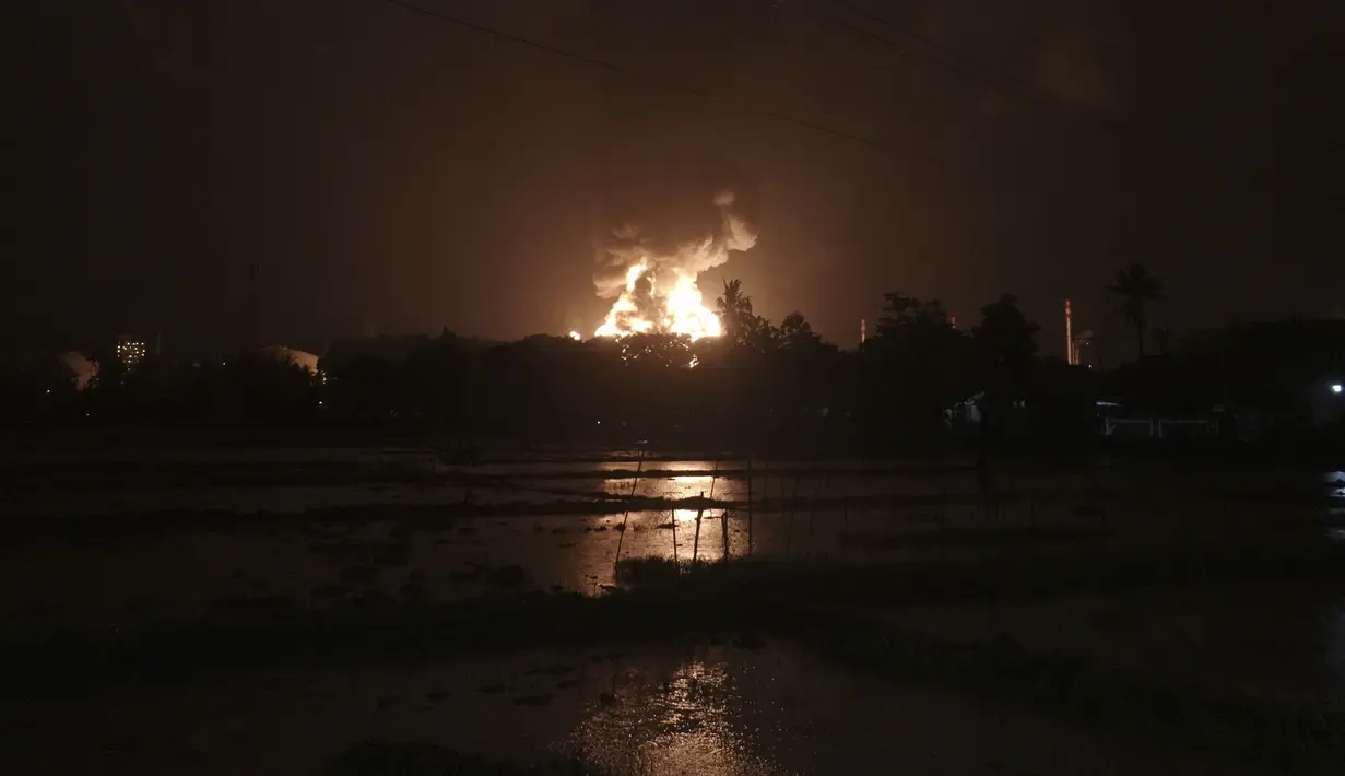 Langit bersinar dari api yang melalap kilang minyak milik Pertamina, di Cilacap, Jawa Tengah, Sabtu (13/11/2021). Kebakaran kilang minyak tersebut membuat puluhan warga yang tinggal di dekatnya dievakuasi. (AP Photo/Agus Fitrah)
