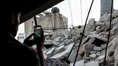 Seorang gamer Suriah menggunakan aplikasi Pokemon Go di ponselnya untuk mencari Pokemons di antara puing-puing di kota Douma, Damaskus (23/7). (AFP PHOTO / Sameer Al-Doumy)