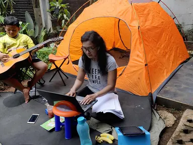 Warga bekerja menggunakan laptop di halaman rumahnya di kawasan Cinere, Depok, Senin (23/3/2020). Imbauan pemerintah untuk bekerja dari rumah atau work from home untuk mencegah penularan virus corona, dimanfaatkan warga dengan beragam aktivitas. (merdeka.com/Arie Basuki)